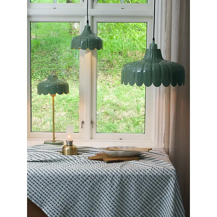 PR Home Pendelleuchte Wells - 25 W, E27 - Zwei glänzend grüne Pendelleuchten mit Wellenrand und eine passende Tischlampe, eine davon leuchtet sanft.