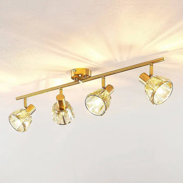 Lindby Deckenleuchte Kosta - L x B x H: 70 x 15,5 x 18 cm, messing / gold, klar / transparent, E14 - Goldfarbene Deckenstrahlerleiste mit vier verstellbaren Leuchten und strukturierten Kristallschirmen, die Lichtmuster an die Decke werfen.