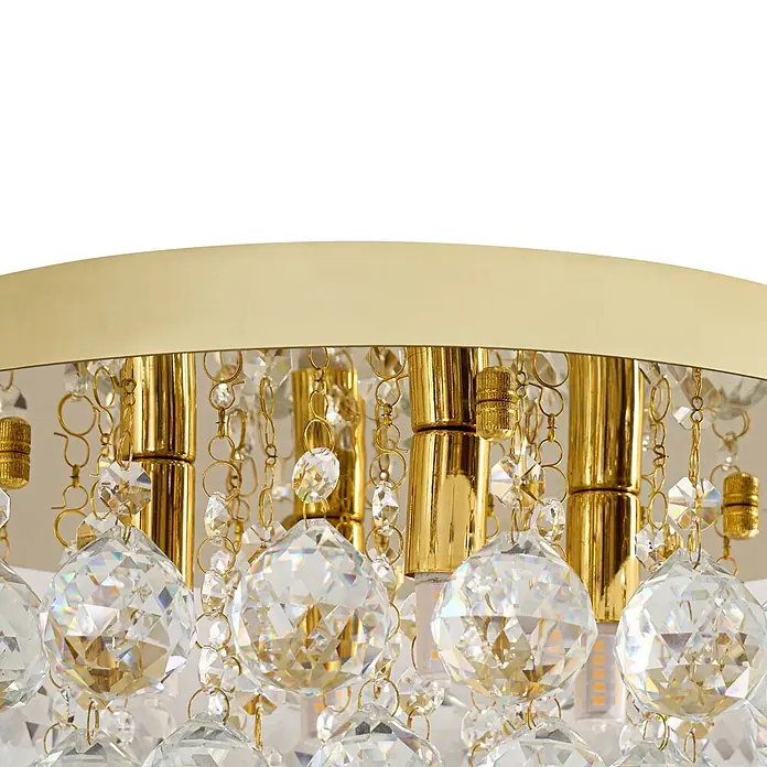 Lindby Deckenleuchte Gillion - messing / gold, klar / transparent, G9 - Nahaufnahme einer goldfarbenen Leuchte mit hängenden facettierten klaren Kristallkugeln und Perlenketten.