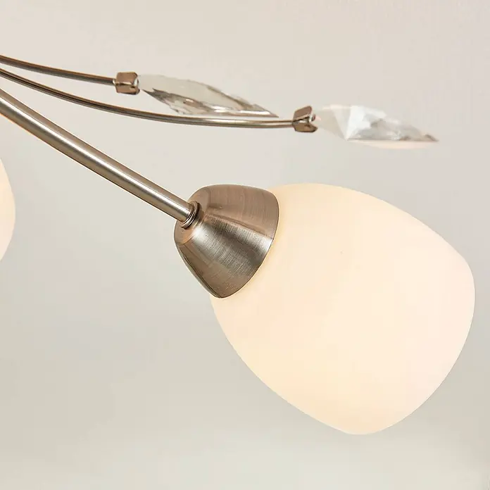 Lindby Deckenleuchte Tatas - weiß / opal, E14 - Nahaufnahme eines Deckenleuchtenarms aus gebürstetem Metall mit mattiertem Glasschirm und klaren dekorativen Kristallelementen.