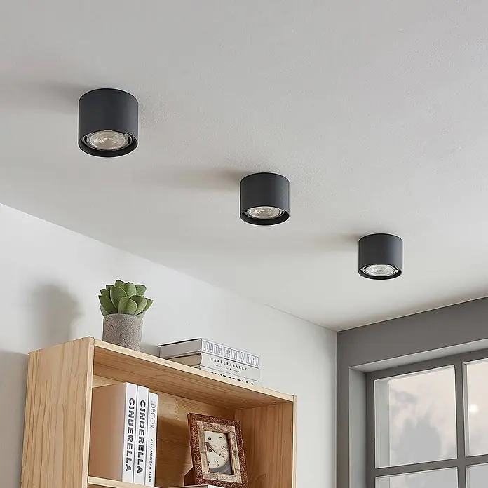 Arcchio Deckenstrahler Mabel - alu / grau / zink, alu / grau / zink, GU10 - Drei schwarze zylindrische Deckenleuchten beleuchten einen modernen Raum.