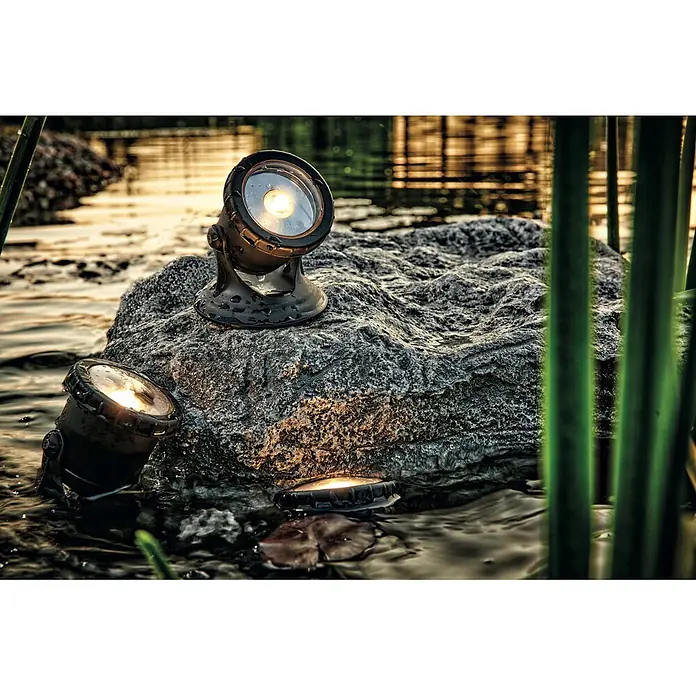 Pontec Teichbeleuchtung PondoStar Set 3 - 1 W, Mit Trafo - Bronze-Außenstrahler auf nassem Felsen, beleuchten Wasser und Felsstruktur. Einer ist teilweise untergetaucht.
