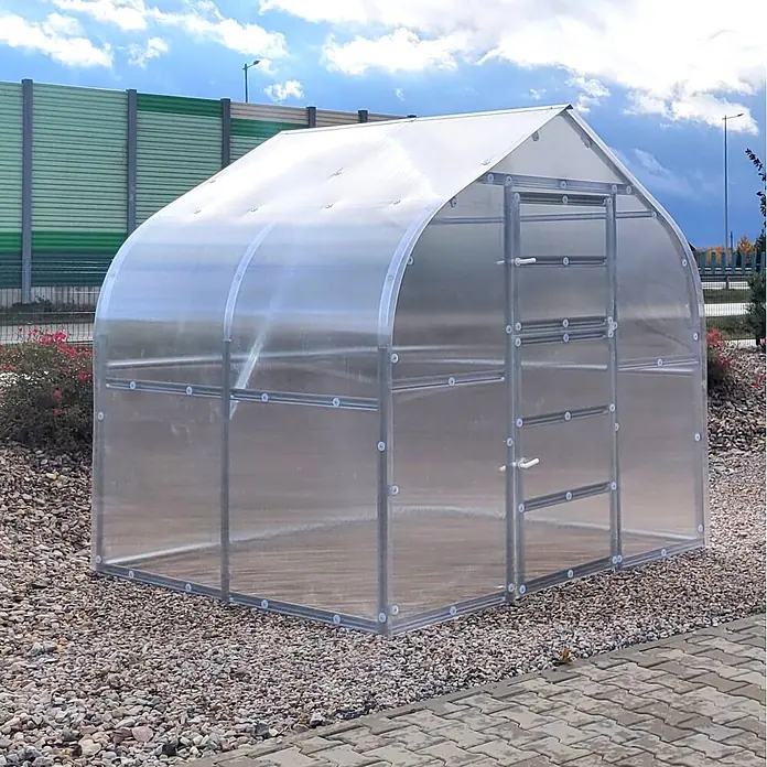 Klasika Greenhouses Gewächshaus Drop Klasika - Außenmaß inkl. Dachüberstand (B x T): 250 x 200 cm, Material Seitenwand: Kunststoff, 6 mm, Silbergrau - Klares Polycarbonat-Gewächshaus mit silbernem Metallrahmen und Bogendach, auf Kies stehend.
