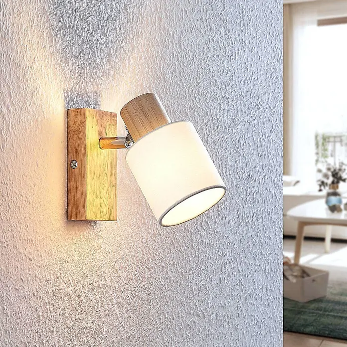 Lindby Deckenstrahler Wanessa - Holz hell, E14 - Moderne Wandleuchte aus hellem Holz und weißem Stoff, mit Chromarm, die ein warmes Licht an eine Wand wirft.