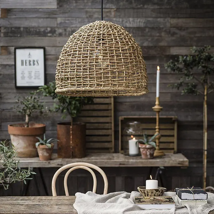 PR Home Pendelleuchte 57cm Outdoor - 40 W, E27 - Natürliche, geflochtene Kuppel-Pendelleuchte, über einem rustikalen Tisch hängend.