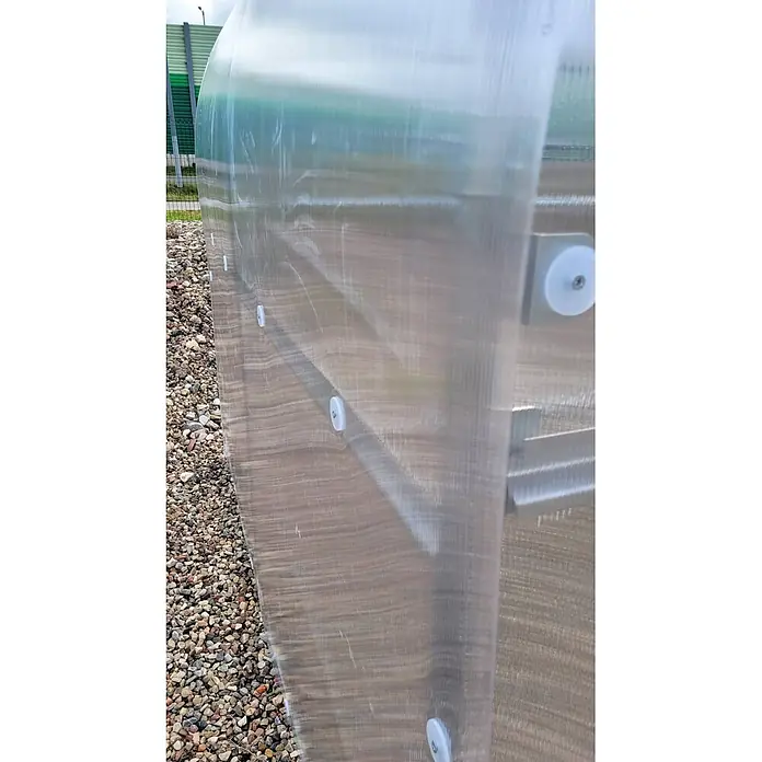 Klasika Greenhouses Gewächshaus Drop Klasika - Außenmaß inkl. Dachüberstand (B x T): 250 x 400 cm, Material Seitenwand: Kunststoff, 4 mm, Silbergrau - Transparente Wellpolycarbonatplatte eines Gewächshauses, mit weißen Befestigungen neben Schotter.