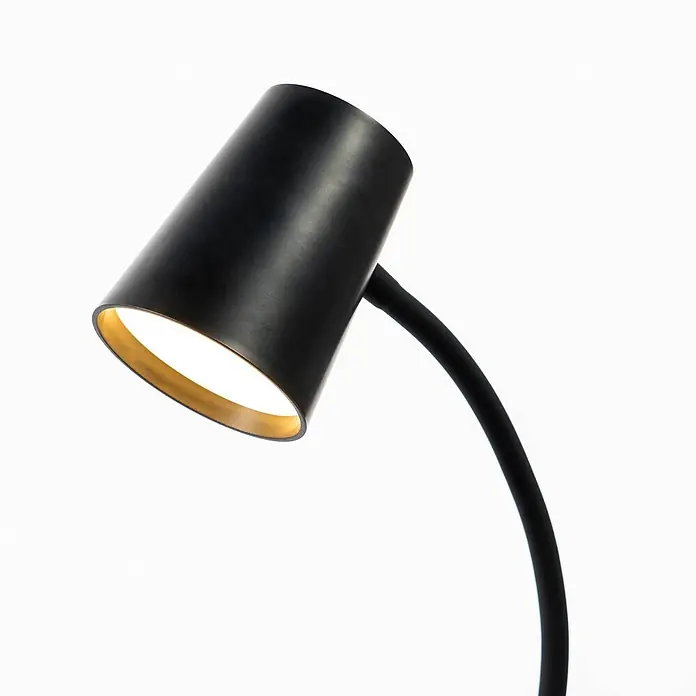 Lindby Klemmleuchte Ailina - Farbe Gehäuse: schwarz - Schwarze konische Lampe mit goldfarbener Innenseite und gebogenem Stiel, die hell leuchtet.