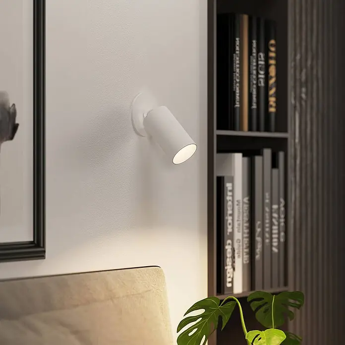 Arcchio Einbauleuchte Davin - weiß / opal, weiß / opal - Weißer Wandstrahler beleuchtet Monstera-Pflanze und Bett in einem gemütlichen Raum.