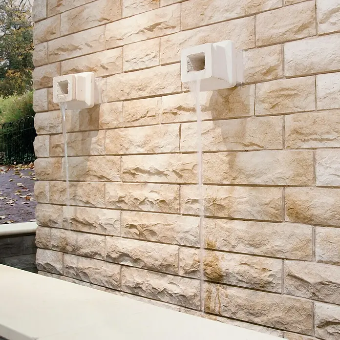 Revestimiento de piedra Cantabria - Pardo, Cantidad total: 4 pzs. - Fuente de agua con dos salidas en una pared de piedra. El agua clara fluye a través de las salidas, creando un efecto decorativo.