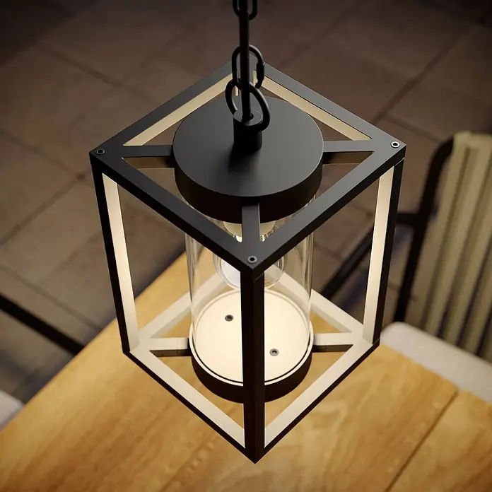 Lucande Außenwand- & Deckenleuchte Ferda - schwarz, schwarz, IP44 - Schwarze Metall-Pendelleuchte mit klarem Glaszylinder, beleuchtet einen Holztisch.