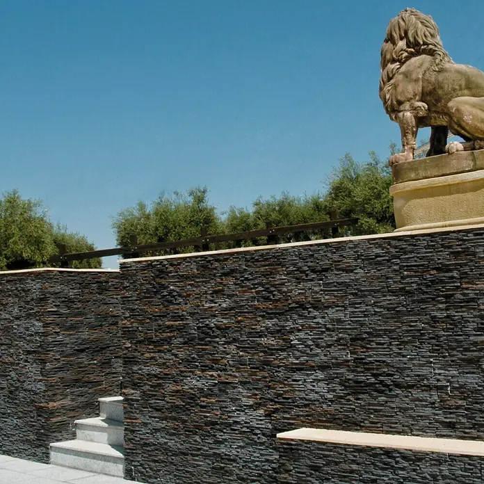 Revestimiento de piedra Galicia - Pizarra, Cantidad total: 4 pzs. - Una impresionante pared de piedra con una estatua de león al fondo, que aporta un toque de grandeza a la escena.