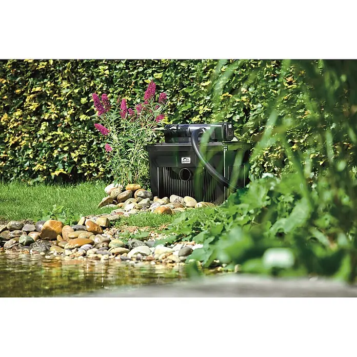 Pontec MultiClear Durchlauffilter-Set MultiClear - Teichgröße: 25.000 l - Schwarzes Pontac Teichfiltersystem neben einem Teich installiert, filtert Wasser.