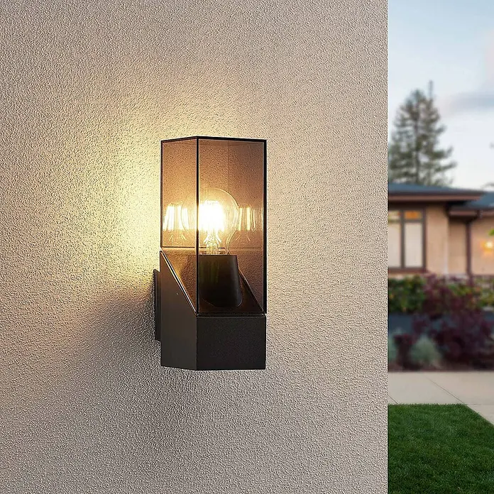 Lucande Außenwandleuchte Fiola - schwarz, IP54 - Schwarze Außenwandleuchte mit Rauchglasschirm, die eine strukturierte Wand warm beleuchtet.