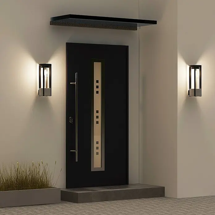 Lucande Außenwandleuchte Overa - alu / grau / zink, alu / grau / zink, IP44 - Moderne Außenwandleuchte mit dunklem Rahmen und grauem Sockel, beleuchtet einen Hauseingang neben einer dunklen Tür.
