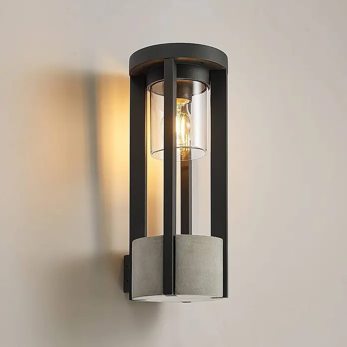 Lucande Außenwandleuchte Overa - alu / grau / zink, alu / grau / zink, IP44 - Schwarz-metallene und Beton-Außenwandleuchte mit klarem Glas und warmer Glühbirne, an der Wand montiert.