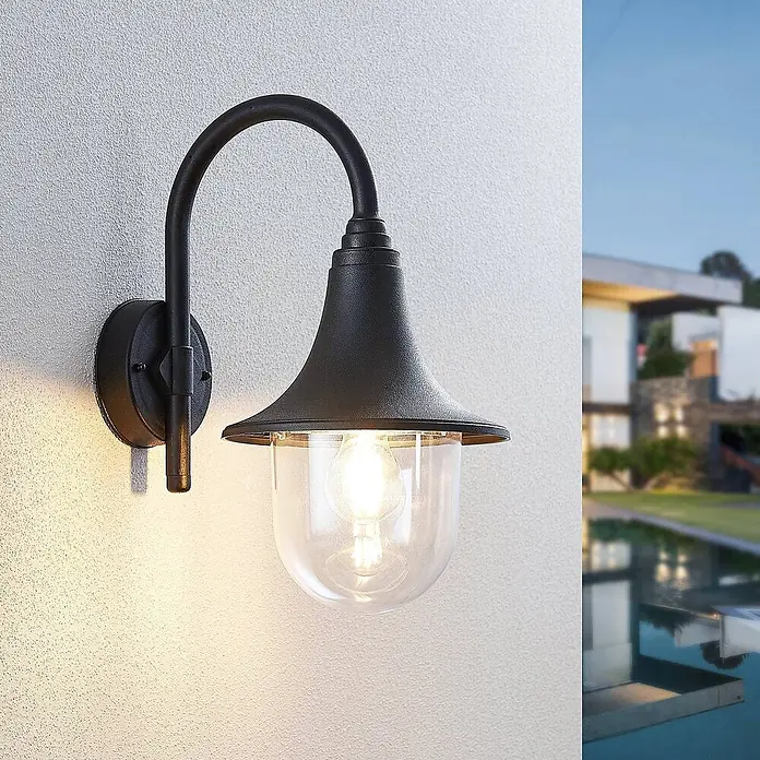 Lindby Außenwandleuchte Nalevi - 32,7 x 21,8 x 40,8 cm, schwarz, schwarz, IP44 - Beleuchtete schwarze Außenwandleuchte mit klarem Glas, an einer Wand montiert, ergänzt ein modernes Haus.