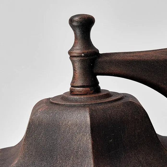 Lindby Außenwandleuchte Lamina - braun / rost, braun / rost, IP44 - Nahaufnahme eines dunkelbraunen, verwitterten Metallornaments mit Knauf und Arm, wahrscheinlich für eine Laterne.