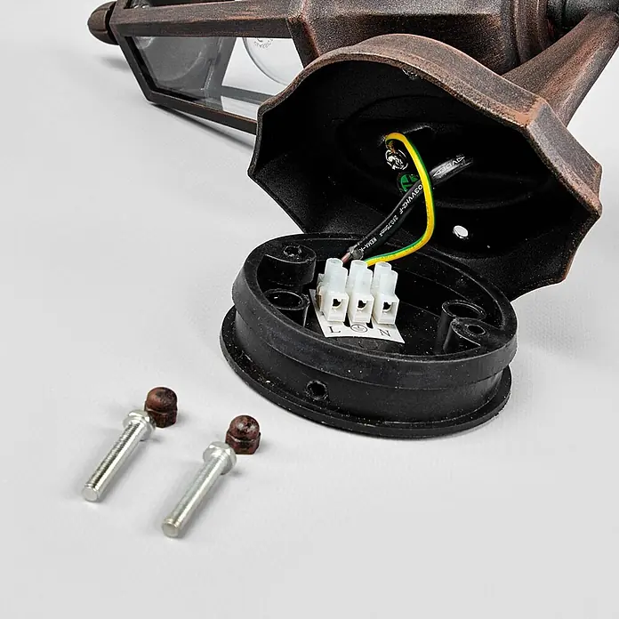 Lindby Außenwandleuchte Lamina - braun / rost, braun / rost, IP44 - Bronzene Außenwandleuchte mit geöffnetem Sockel, der elektrische Anschlüsse und Befestigungsschrauben zeigt.