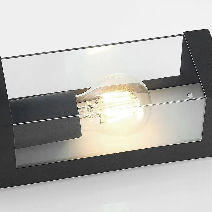 Lindby Außenwandleuchte Tilian - alu / grau / zink, alu / grau / zink, IP44 - Schwarze Außenwandleuchte mit Klarglas, zeigt eine leuchtende Glühbirne.