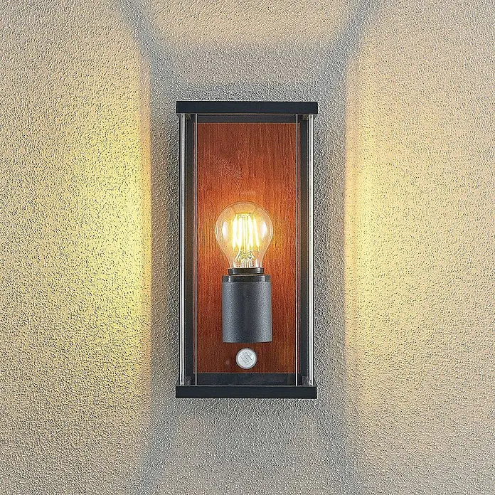 Lucande Außenwandleuchte Elwin - 16,4 x 14 x 29 cm, schwarz, schwarz, IP54 - Wandleuchte mit schwarzem Rahmen, Holzrückwand, Klarglas, sichtbarer Glühbirne und Bewegungsmelder an einer strukturierten Wand.