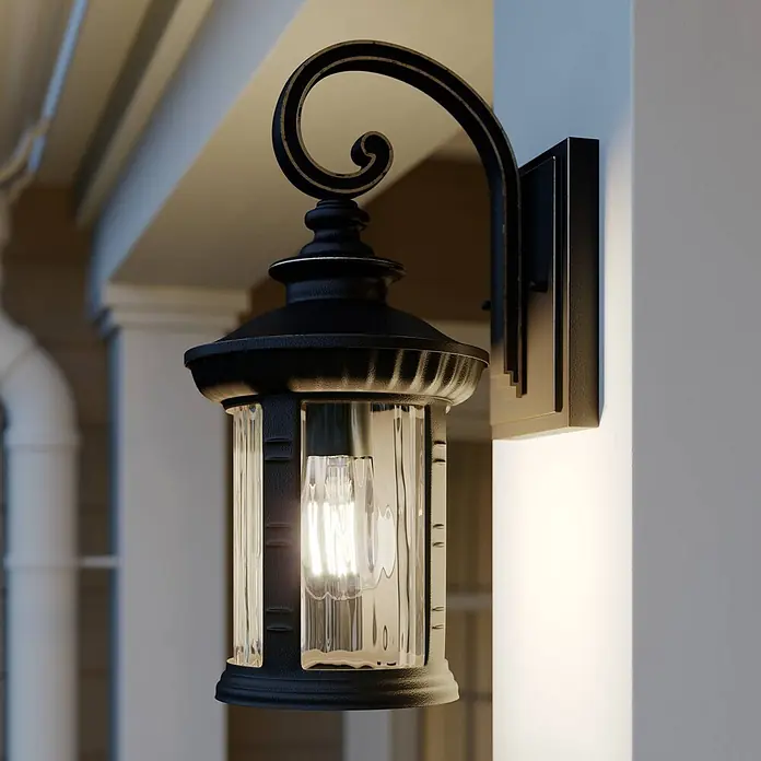 Lindby Außenwandleuchte Barret - braun / rost, IP23 - Schwarze Außenwandleuchte mit dekorativem Schnörkelarm, klarem Riffelglas und sichtbarer Glühbirne, an einer Wand montiert.
