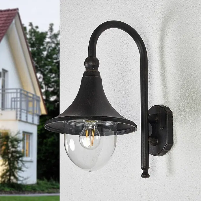 Lindby Außenwandleuchte Daphne - 35,5 x 24,5 x 44,2 cm, schwarz, schwarz, IP44 - Dunkle Bronze Außenwandleuchte mit klarem Glas und Filamentbirne an einer Hauswand.