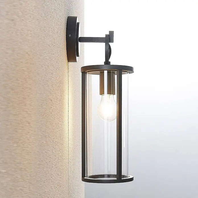 Lucande Außenwandleuchte Emmeline - 17,8 x 14,5 x 45 cm, schwarz, IP54 - Schwarze Metall-Wandleuchte mit klarem Glaszylinder und leuchtender Glühbirne.