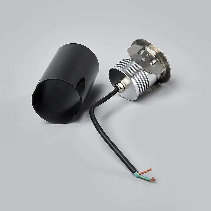 Lucande LED-Gartenstrahler Helene - 3.000 K, 8,8 x 8,8 x 9,5 cm - Eine silberne Einbau-Außenleuchte mit schwarzem zylindrischem Gehäuse und freiliegenden elektrischen Kabeln.