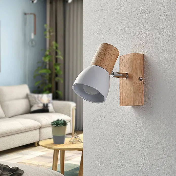 Lindby Wandstrahler Thorin - Holz hell, E14 - Weiße und hellholzige Wandleuchte mit schwenkbarem Kopf, montiert an einer strukturierten Wand in einem modernen Wohnzimmer.