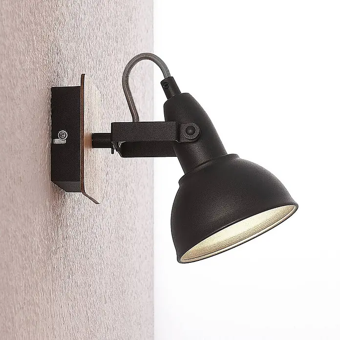 Lindby Wandstrahler Aylis - Holz dunkel, schwarz, E14 - Schwarzer, verstellbarer Wandstrahler mit Metallschirm und Holzsockel, an strukturierter Wand montiert.