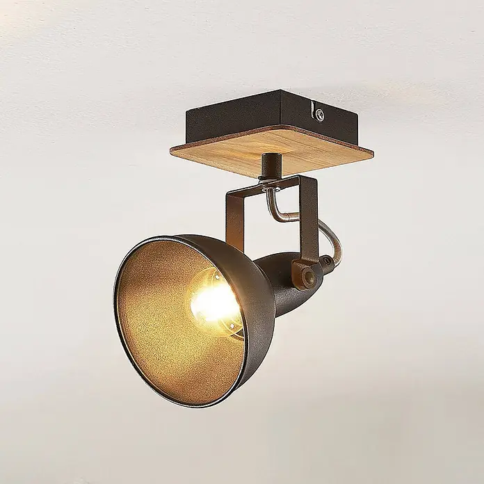 Lindby Wandstrahler Aylis - Holz dunkel, schwarz, E14 - Verstellbarer schwarzer Deckenstrahler aus Metall mit Holzbasis und goldener Innenseite, leuchtende Birne sichtbar.