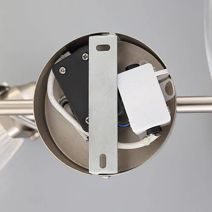 Lindby Wandleuchte Kara - alu / grau / zink, G9 - Innenansicht des Leuchtenfußes mit silbernem Metall, schwarzen und weißen elektrischen Komponenten und geflochtenen Kabeln.