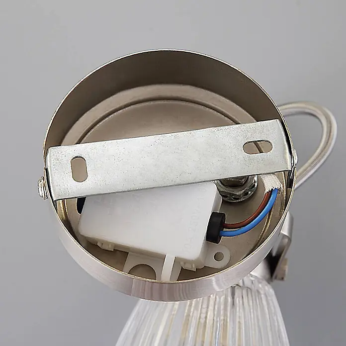 Lindby Wandleuchte Kara - L x B x H: 14 x 9 x 21 cm, alu / grau / zink, G9 - Innenansicht einer silbernen Leuchtenbasis mit Montagebügel, weißem Elektrogehäuse und freiliegenden blauen und braunen Kabeln.