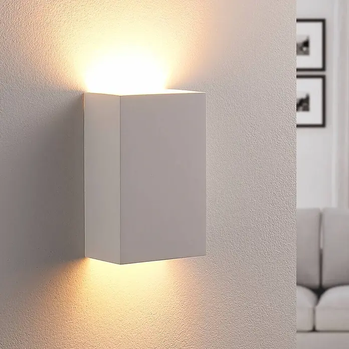 Lindby Wandleuchte Colja - weiß / opal, G9 - Weiße, rechteckige Wandleuchte, montiert an einer strukturierten Wand, strahlt warmes Licht nach oben und unten.