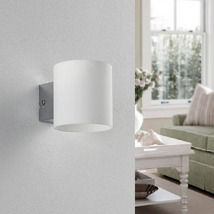 Lindby Wandleuchte Gerrit - L x B x H: 12,2 x 9,2 x 9,5 cm, weiß / opal, G9 - Weiße zylindrische Wandleuchte an einer strukturierten Wand, spendet sanftes Licht in einem Wohnzimmer.