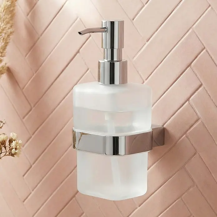 Lenz Aura Seifenspender - Mit Halterung, Chrom, Glänzend - Wandmontierter Seifenspender mit Chrompumpe und mattierter Glasflasche vor einer rosa Fischgrätenfliesenwand.