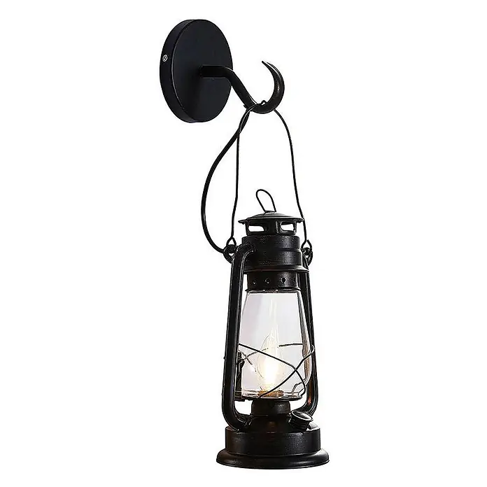 Lindby Wandleuchte Raisa - braun / rost, E14 - Rustikale Wandleuchte mit dunkler, gealterter Metalllaterne, klarem Glasschirm und sichtbarer Glühbirne, an passendem Wandhaken hängend.