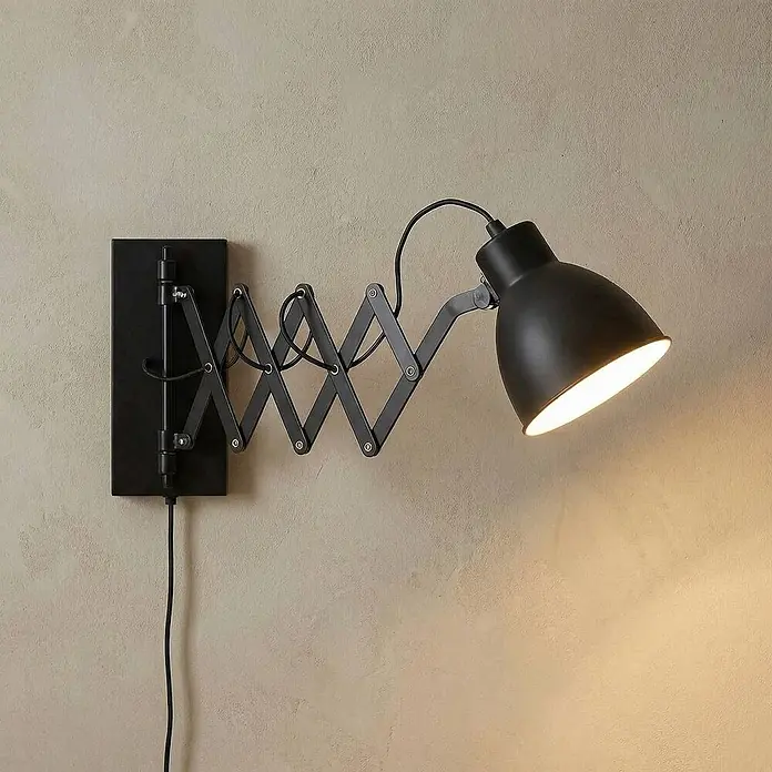Lindby Wandleuchte Merle - schwarz, schwarz, E14 - Schwarze Metall-Wandlampe mit verstellbarem Scherengelenk, beleuchtet eine strukturierte Wand darunter.