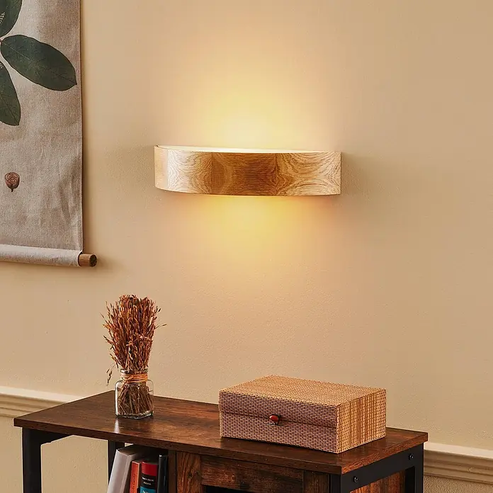 Envostar Wandleuchte Kerio - L x B x H: 11,5 x 40,5 x 8 cm, Holz hell, E27 - Holz-Wandlampe mit heller Holzmaserung, wirft warmes Licht nach oben und unten an eine beige Wand.