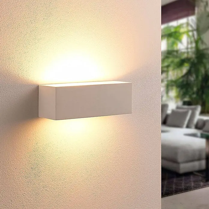 Lindby Wandleuchte Tjada - L x B x H: 7,5 x 21,8 x 7,5 cm, weiß / opal, G9 - Weiße rechteckige Up-Down-Wandleuchte, die warmes Licht auf eine strukturierte Wand in einem Wohnraum wirft.