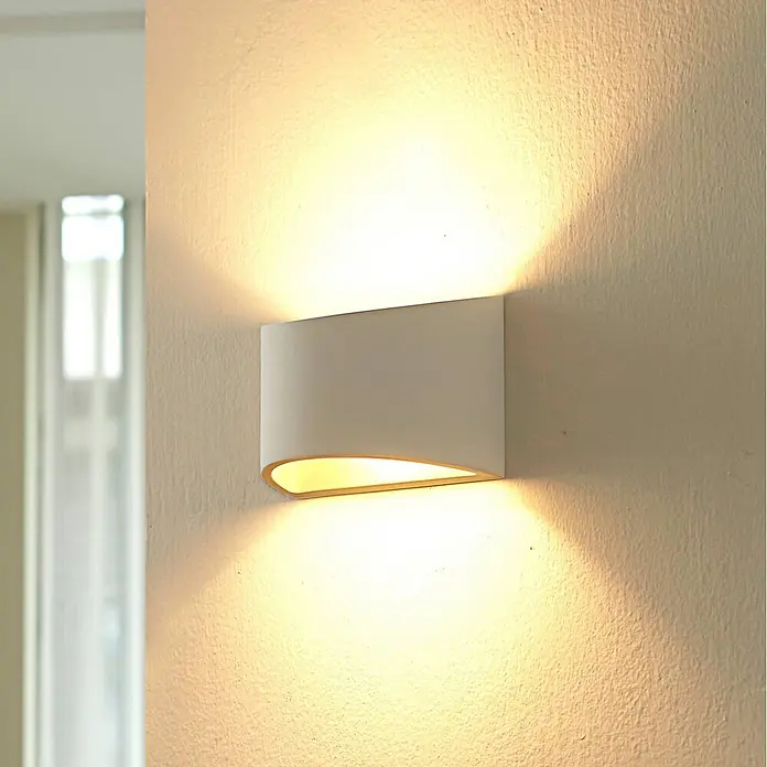 Lindby Wandleuchte Heiko - L x B x H: 8,5 x 20 x 12 cm, weiß / opal, G9 - Weiße Wandleuchte an einer strukturierten Wand, die warmes Licht nach oben und unten wirft.