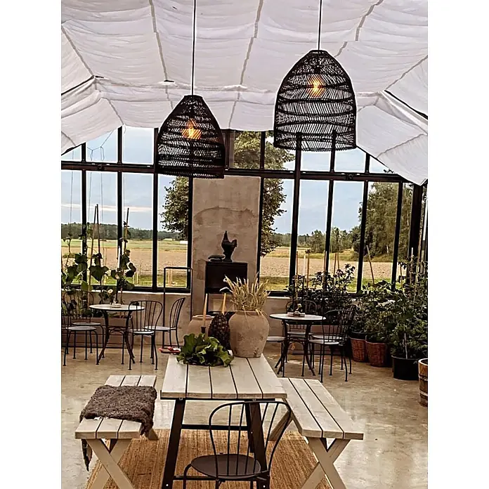 PR Home Pendelleuchte schwarz 45cm Outdoor - 40 W, E27 - Zwei große, dunkle geflochtene Pendelleuchten hängen von einer Stoffdecke in einem hellen Gewächshaus-Essbereich.
