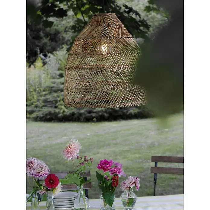 PR Home Pendelleuchte Natur 53cm Outdoor - 40 W, E27 - Eine beleuchtete Pendelleuchte aus natürlichem Rattan hängt im Freien über einem Tisch und verleiht der Umgebung einen warmen Glanz.