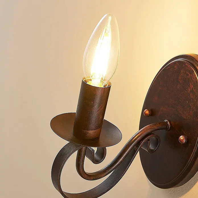 Lucande Wandleuchte Caleb - braun / rost, braun / rost, E14 - Rustikale Wandleuchte aus dunkler Bronze mit einer einzelnen, leuchtenden, kerzenförmigen Glühbirne.