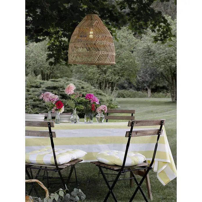 PR Home Pendelleuchte Natur 53cm Outdoor - 40 W, E27 - Natürliche Pendelleuchte aus geflochtenem Korbgeflecht mit sichtbarer Glühbirne, hängt über einem Esstisch im Freien mit Blumendekoration.