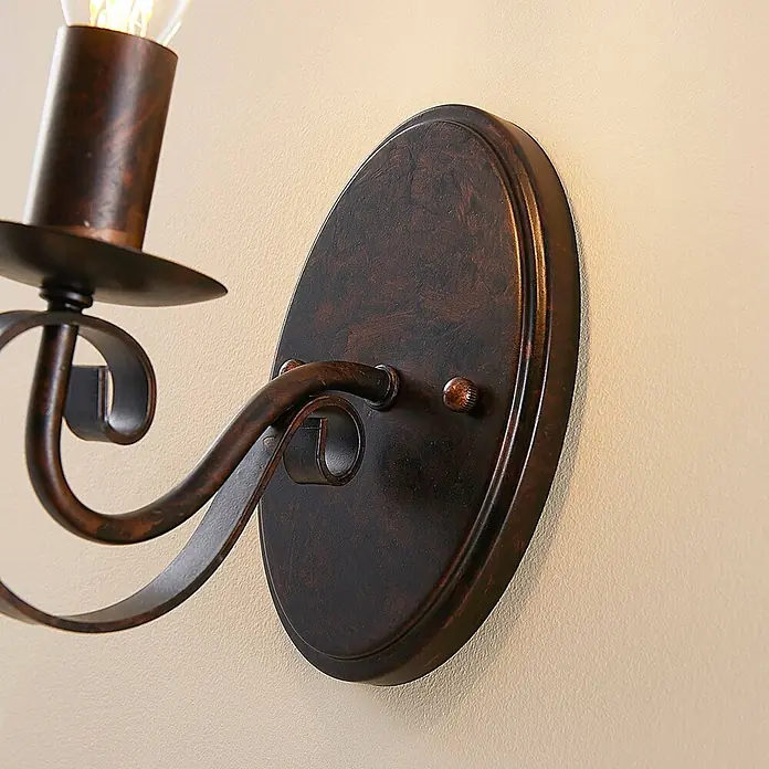 Lucande Wandleuchte Caleb - braun / rost, braun / rost, E14 - Wandleuchte aus dunkler Bronze mit kerzenförmigem Licht und dekorativem Scrollarm.
