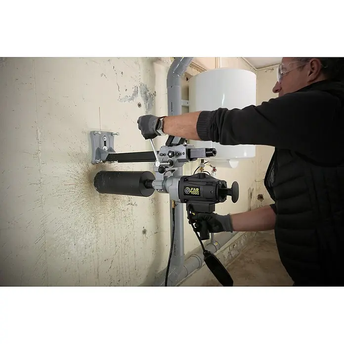 Fartools Taladro perforador de corona CB 2300S - 2.300 W, Diámetro de taladrado máx. en hormigón: 180 mm - Máquina de perforación de núcleos FAR TOOLS gris y negra en uso, perforando un gran agujero en una pared.