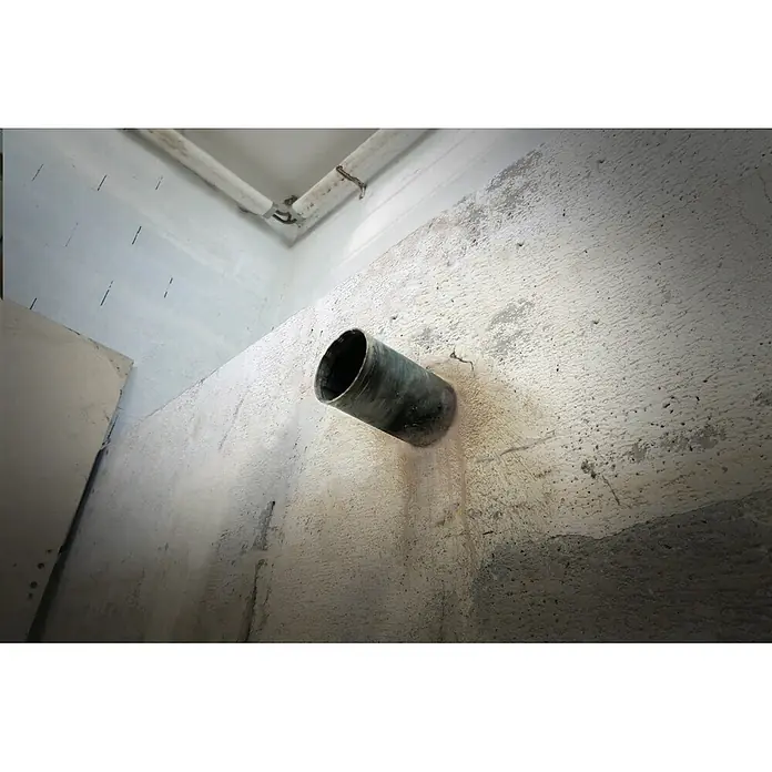 Fartools Taladro perforador de corona CB 2300S - 2.300 W, Diámetro de taladrado máx. en hormigón: 180 mm - Tubo metálico oscuro que sobresale de una pared de hormigón rugoso, parte de un sistema de drenaje o ventilación.