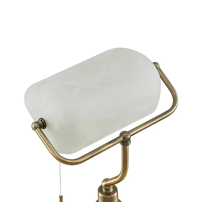 Lindby Tischleuchte Profina - L x B x H: 18,5 x 27,2 x 38,5 cm, bronze / altmessing, weiß / opal, E27 - Nahaufnahme einer Lampe mit matt-weißem Glasschirm und antikem Messingrahmen, ausgestattet mit Zugschalter.