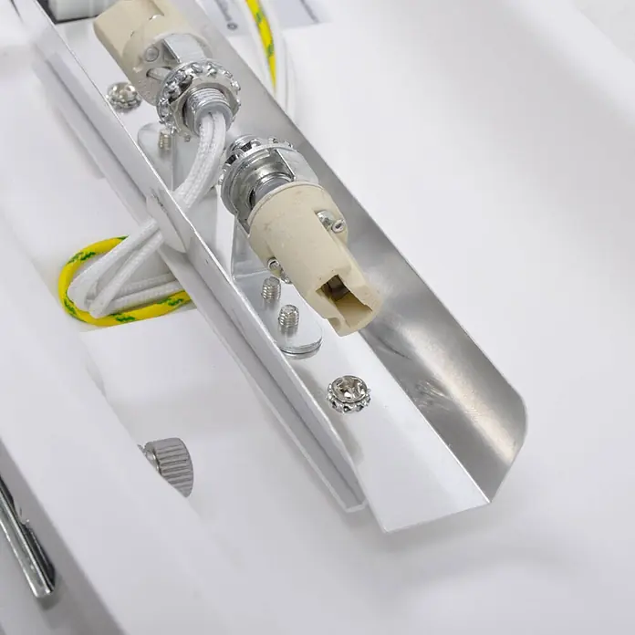 Lindby Wandleuchte Leander - weiß / opal, G9 - Innenansicht einer Leuchte mit zwei Keramiklampenfassungen, weißen Geflechtschnüren und einem gelb-grünen Erdungskabel in einem silbernen Metallkanal.